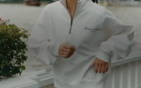 A model wearing the Mandarin Oriental Bangkok x Sporty & Rich 150th-anniversary capsule in a hotel setting.